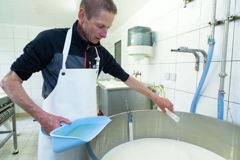 An image showing a man adding rennet to milk