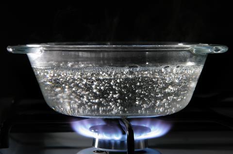 A glass dish of boiling water on a gas hob