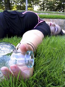 A person passed out on the ground, holding a bottle