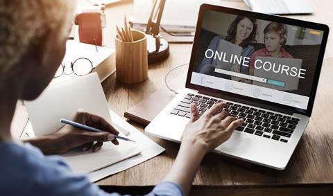 A women with pencil and paper looking at a laptop which has 'Online course' on the screen