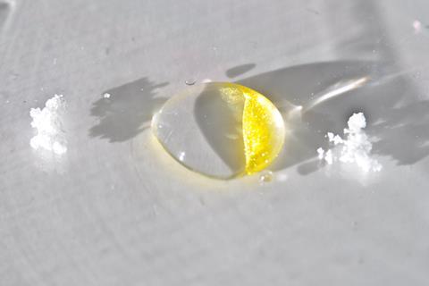 In a drop of liquid two white crystal substances dissolve and form a yellow crystal