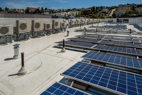 A sunny building roof with solar panels and air conditioning units