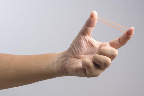 A hand stretching a rubber band between thumb and forefinger