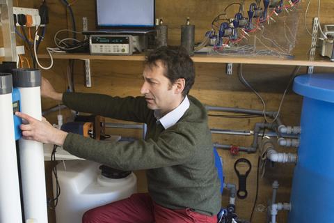 Scientist with water purification equipment and laptop in shed