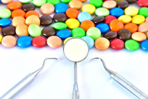 Sweets lined up on a table with a set of dental tools in front