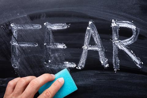 An image showing the word FEAR written in chalk and partially erased with a sponge