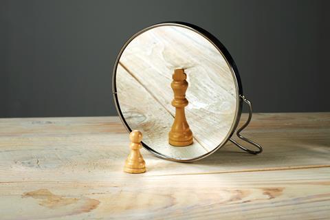A pawn before a mirror, reflected as a king
