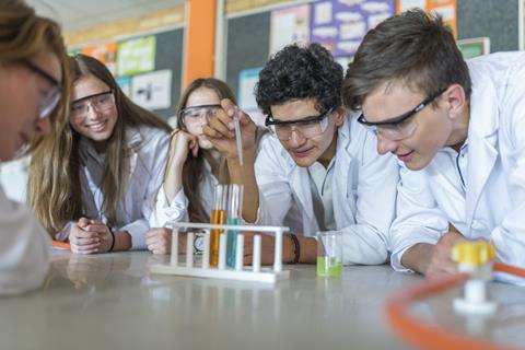 A group of A-level students doing a practical experiment, boy using a pipette to add to a test tube.