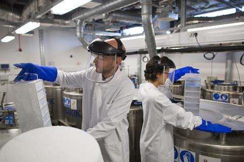 Two scientists work in a lab in protective gloves and masks
