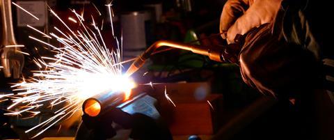 Doing metalwork using an oxyacetylene torch with a bright flame and sparks