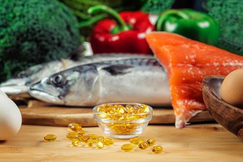 A photo of eggs, oily fish, vegetables and golden supplement capsules