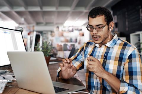 Man with heaphones in front of a laptop and desktop computer