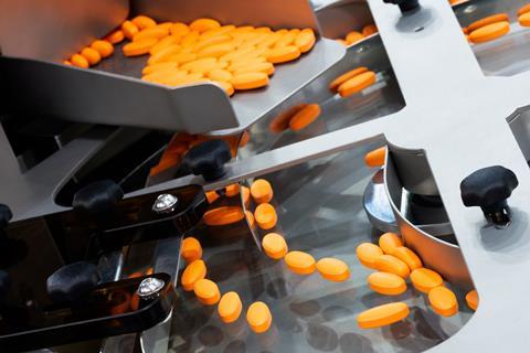 Orange vitamin supplement tablets on a production line