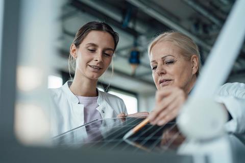 Two scientists examining the surface of a solar panel in a lab