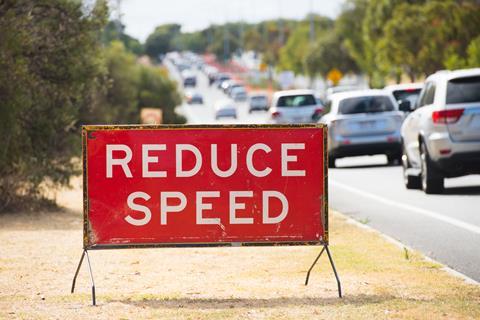 A large, red 'reduce speed' sign beside a road