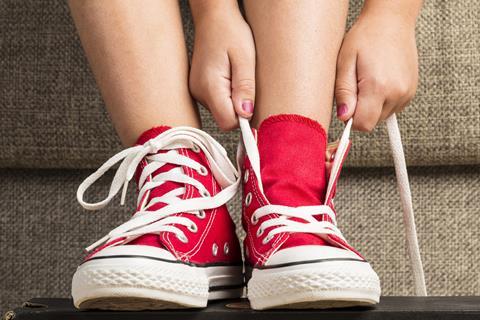 Child tying shoelaces on red American sneakers