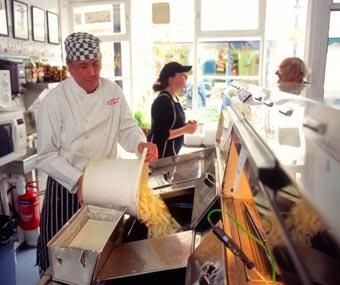 A cook preparing chips for serving