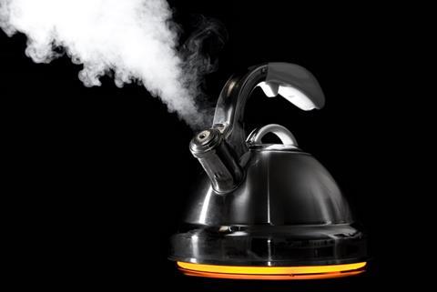 Black background, old-fashioned style kettle emitting vapour