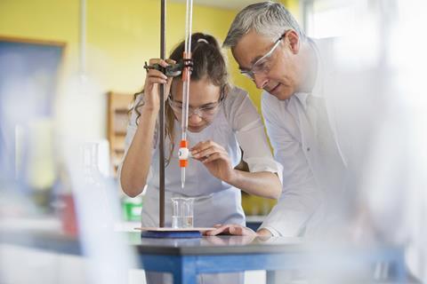 A photo showing a chemistry teacher helping a student with a titration