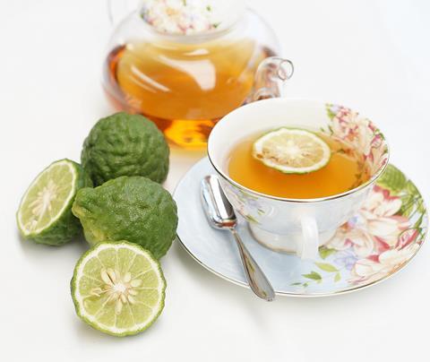 A photo showing a cup of Earl Grey tea next to cut out bergamots
