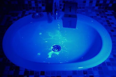 Spots of luminol glowing under a UK light in a sink indicating blood