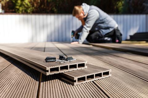 A man uses an electric drill and composite materials to create a patio in a garden
