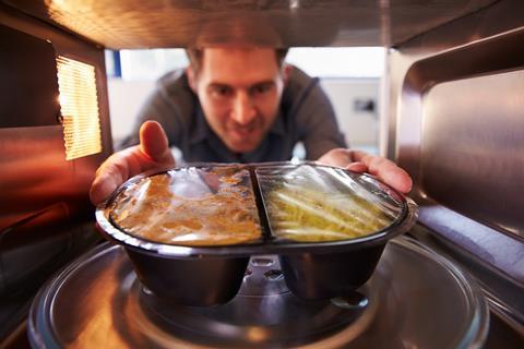 An image showing a man placing food in a microwave oven