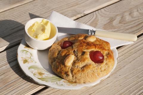 A photo of a rock cake with cherries and almonds on top on a plate