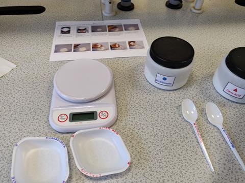 A photo of equipment and step-by-step instructions on a workbench for a practical chemistry experiment; the dishes, labels and containers are colour coded