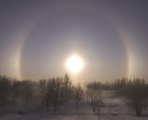 A sun halo visible over a wintery, snow-covered landscape
