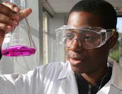 A science student looking at a flask filled with a pink liquid