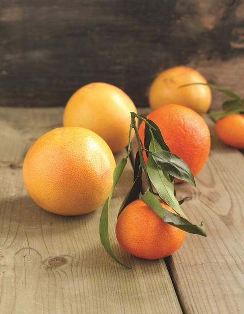 Oranges and orange tree leaves on a wooden table