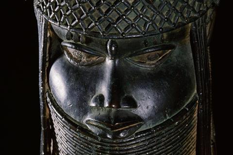A close up of the face of a bronze statue of a richly decorated head