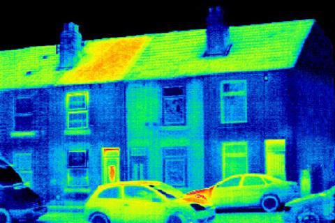A thermogram of a row of houses on a street showing one house is leaking heat through its roof, windows and door.