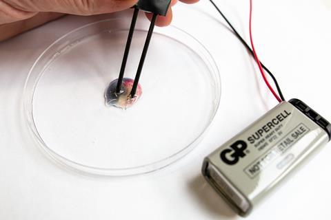 A close up photo of a drop of liquid in a petri dish and a battery