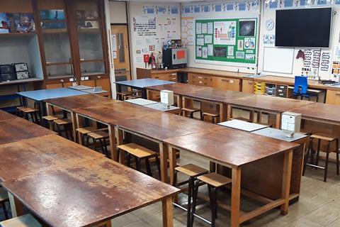 A school lab with desks, stools and a fume cupboard