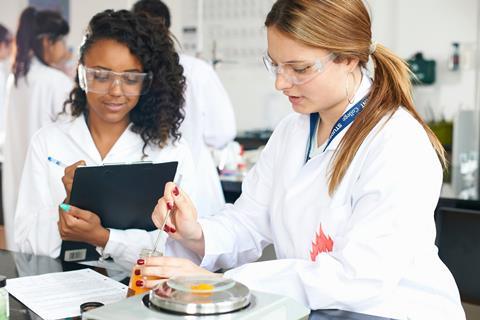 Two female high school students measuring chemicals in a school lab