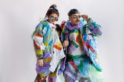 Man and woman fashionistas dressed a=in bright plastic waste and wearing sunglasses