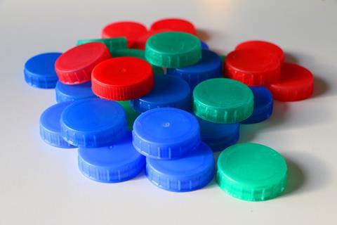 A pile of plastic milk bottle tops in red blue and green