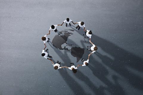 An image showing children holding hands gathered in a circle around a drawing of Planet Earth