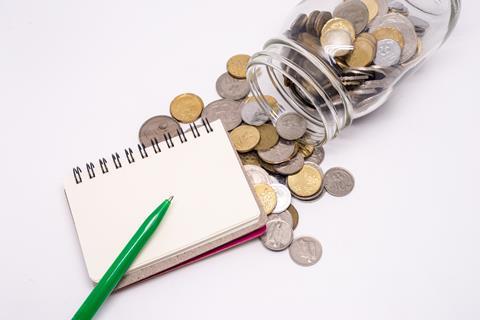 Jar of coins next to notebook with a pen