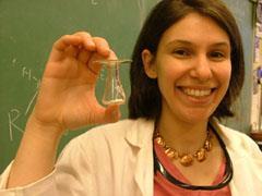 A student smiling and holding a glass tube