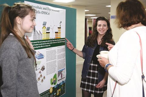 Three people gathered round a scientific poster