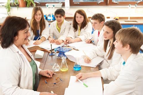 Group of teenage students in a science class with teacher