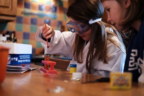 Two girls with a hobby chemistry set in a domestic kitchen