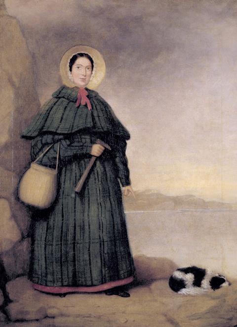 A painting of Mary Anning holding a hammer with her dog, at the base of a cliff by the sea