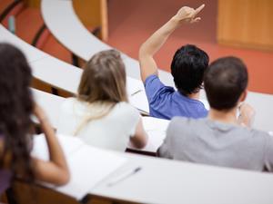 Students raising hands in a lecture theatre