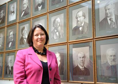 Professor Yellowlees standing in front of past portraits of RSC Presidents