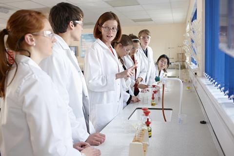 Teacher and several students along a bench in a chemistry lab
