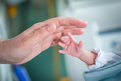 A picture showing the hand of an adult reaching for the small hand of a prematurely born baby